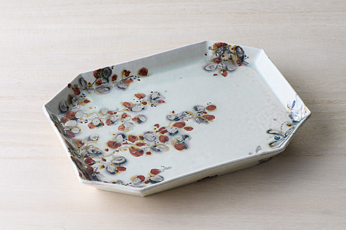 余白を生かして植物が描かれており、まるで日本画を鑑賞しているような美しさを持つ長皿です。植物は抽象化されており、季節を問わずお使いいただけます。   緑釉白金赤絵隅切四方長皿 税込¥88,000（26.5×19.5×3.6㎝）