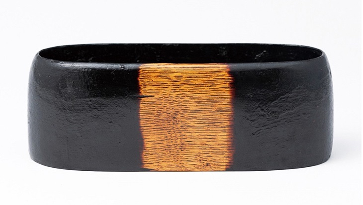「栗拭漆黒楕円盛器」 サイズ：タテ11.5×ヨコ29.5×高さ10.5cm  中央は黒色を抜き、木目との色の対比が作品全体を引き締めて見せます。今の自分のくらしの中で楽しめる器作りを目指す、作者の代表的な作域の一つです。