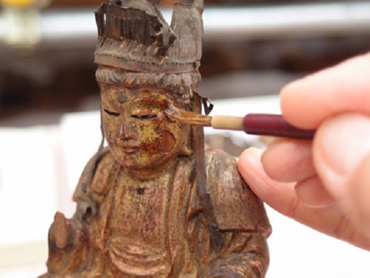 金銅装山伏笈（奈良国立博物館）に付属する五仏像に剥落止めを施す様子