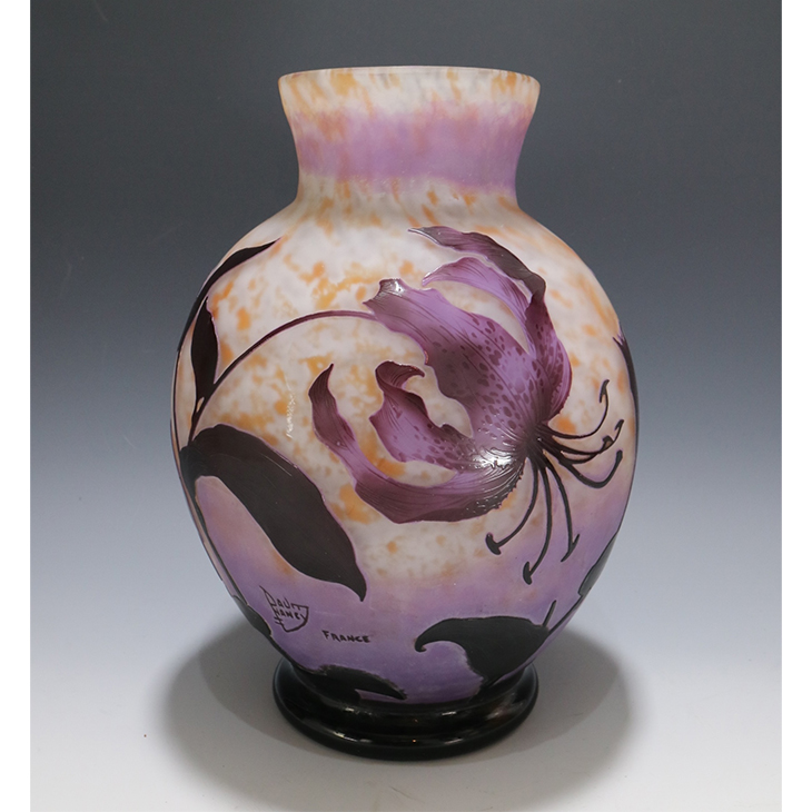 ドーム／ユリ文花瓶 サイズ：高さ33cm 制作年：1895年頃 花言葉：「純粋」「無垢」 12月21日の誕生花です。オレンジを練り込んだピンク地に紫を被せ、エッチングで百合の花を彫刻した作品です。安定感ある形状に描かれた百合の大輪が大変美しく、力強い作品です。