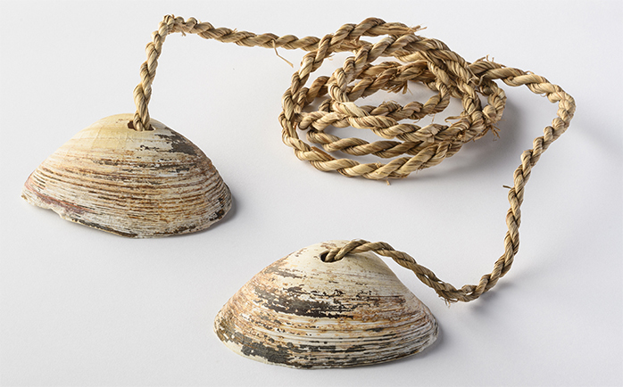 貝下駄　セイピラッカ 国立アイヌ民族博物館蔵 ウバガイ（ホッキガイ）で作る遊具。両足の親指と人差し指の間に縄を挟んで貝殻に乗り、歩いて遊ぶ。