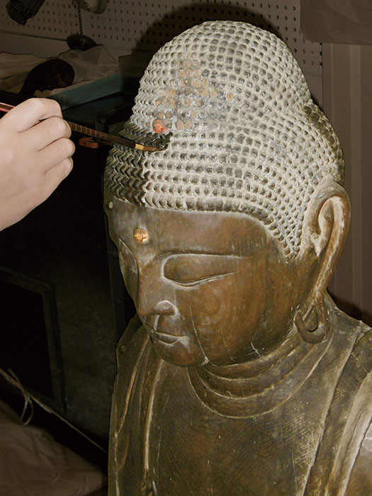 修理作業の様子　泉屋博古館蔵《阿弥陀如来坐像》　後補彩色層の剥落止め